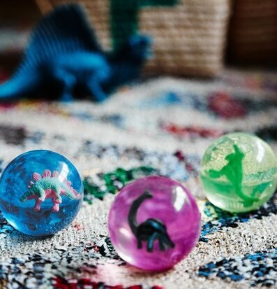 Studsboll Dinosaurie från Rice på färgglad matta med korg