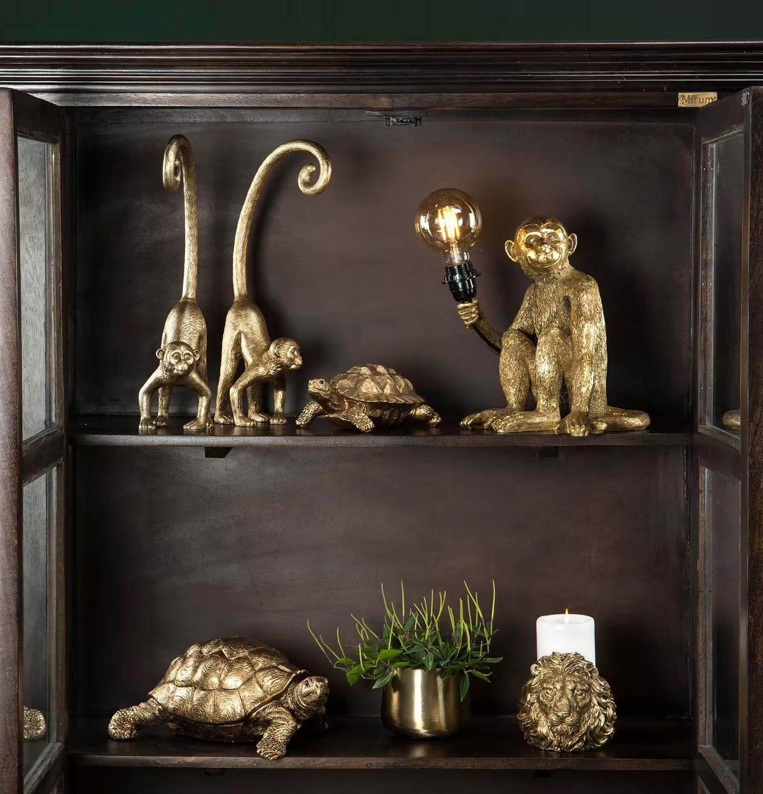 Lampa Apa Guld från A Lot Decoration i ett mörkt trähylla