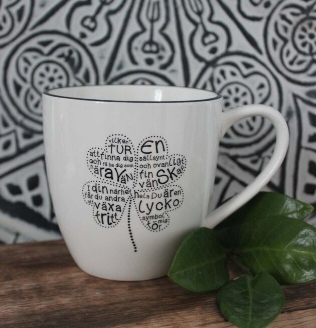 Mugg Vänskap - Majas Cottage på träyta med gröna blad