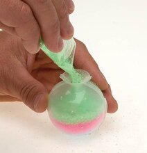 Hand häller grönt pulver i form för Gör en egen studsboll från Worldwide co