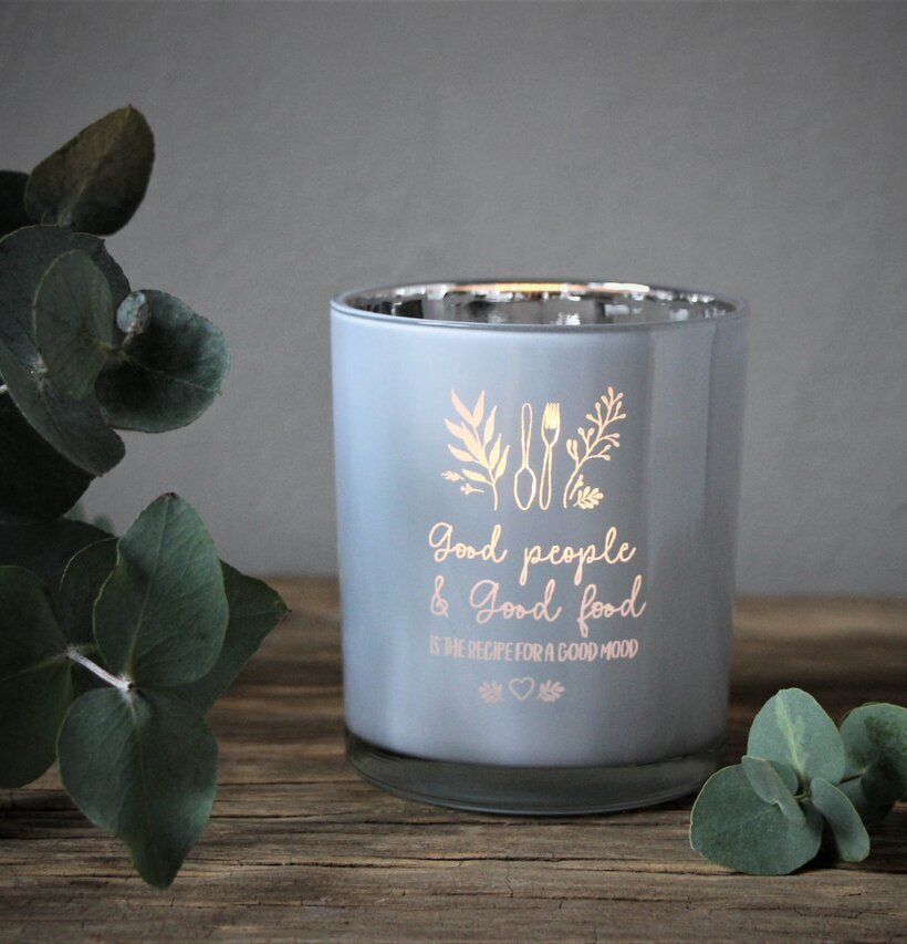 Foto av ljuslykta på rustikt bord med eukalyptusblad