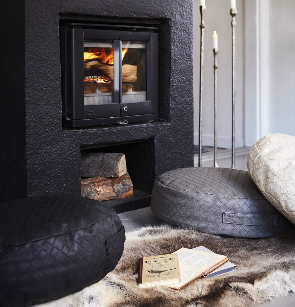Sittpuff Holly Grå från Affari framför svart öppen spis