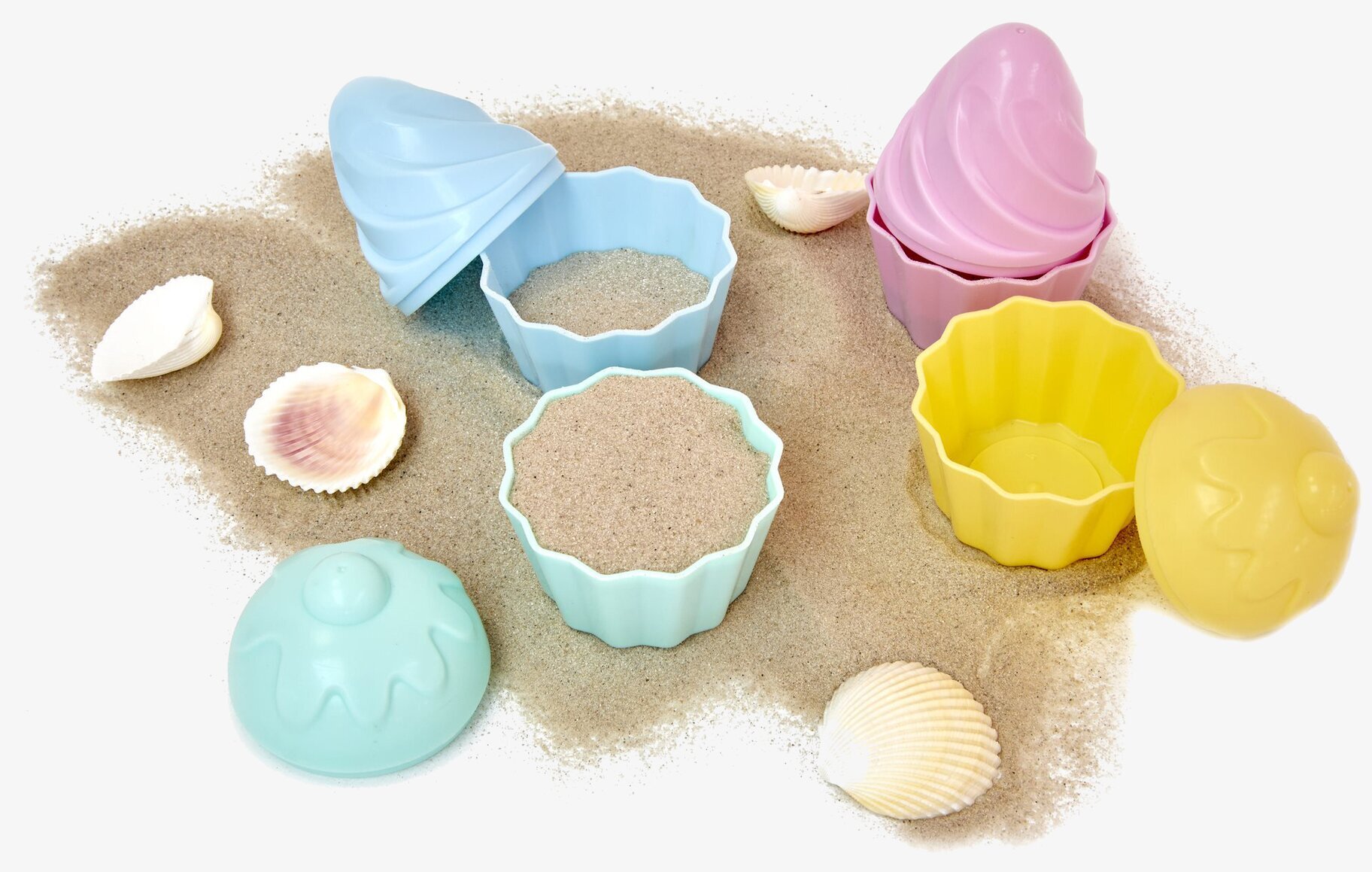 Sandformar Cupcakes från Rice på sandig yta med snäckskal