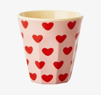 Foto av en mugg med hjärtmönster och rosa bakgrund