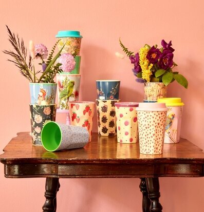 Bild av färgglada koppar på antikt träbord i rosa miljö