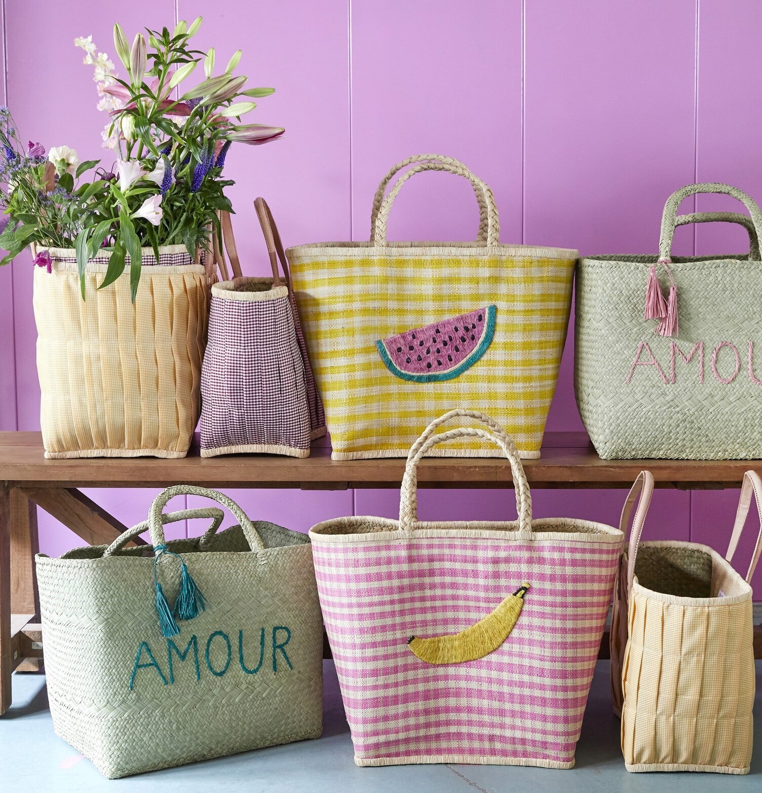 Väska Check Raffia M från Rice på träbänk med andra väskor