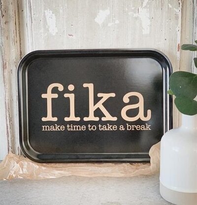 Bricka Fika Svart/Guld från Mellow Design framför trädvägg