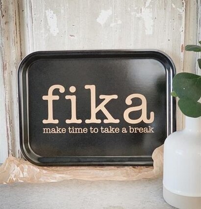 Bricka Fika Svart/Guld från Mellow Design framför trädvägg