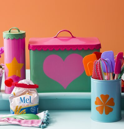 Bild med färgglada plåtburkar och blomsterarrangemang