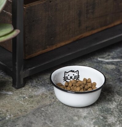 Kattskål Emalj från IB Laursen på ett stengolv med växt