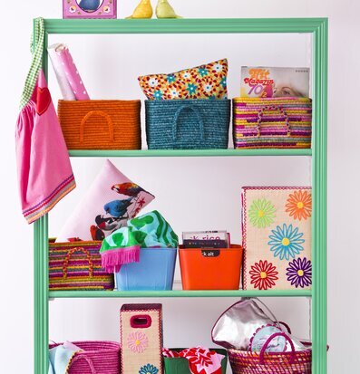 Raffiakorg Multi från Rice på grön hylla med färgglada kuddar