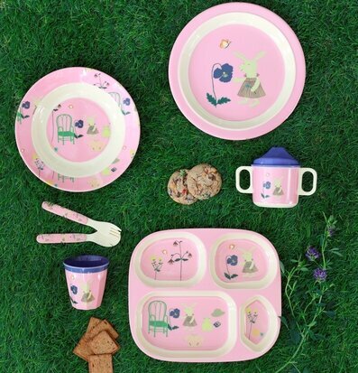 Foto av barnservis i pastell på grön gräsmatta