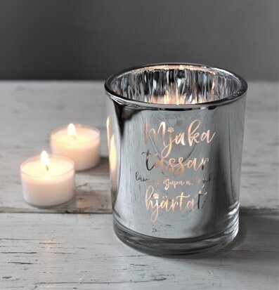 Bild av en ljuslykta med silverfinish och tassmotiv