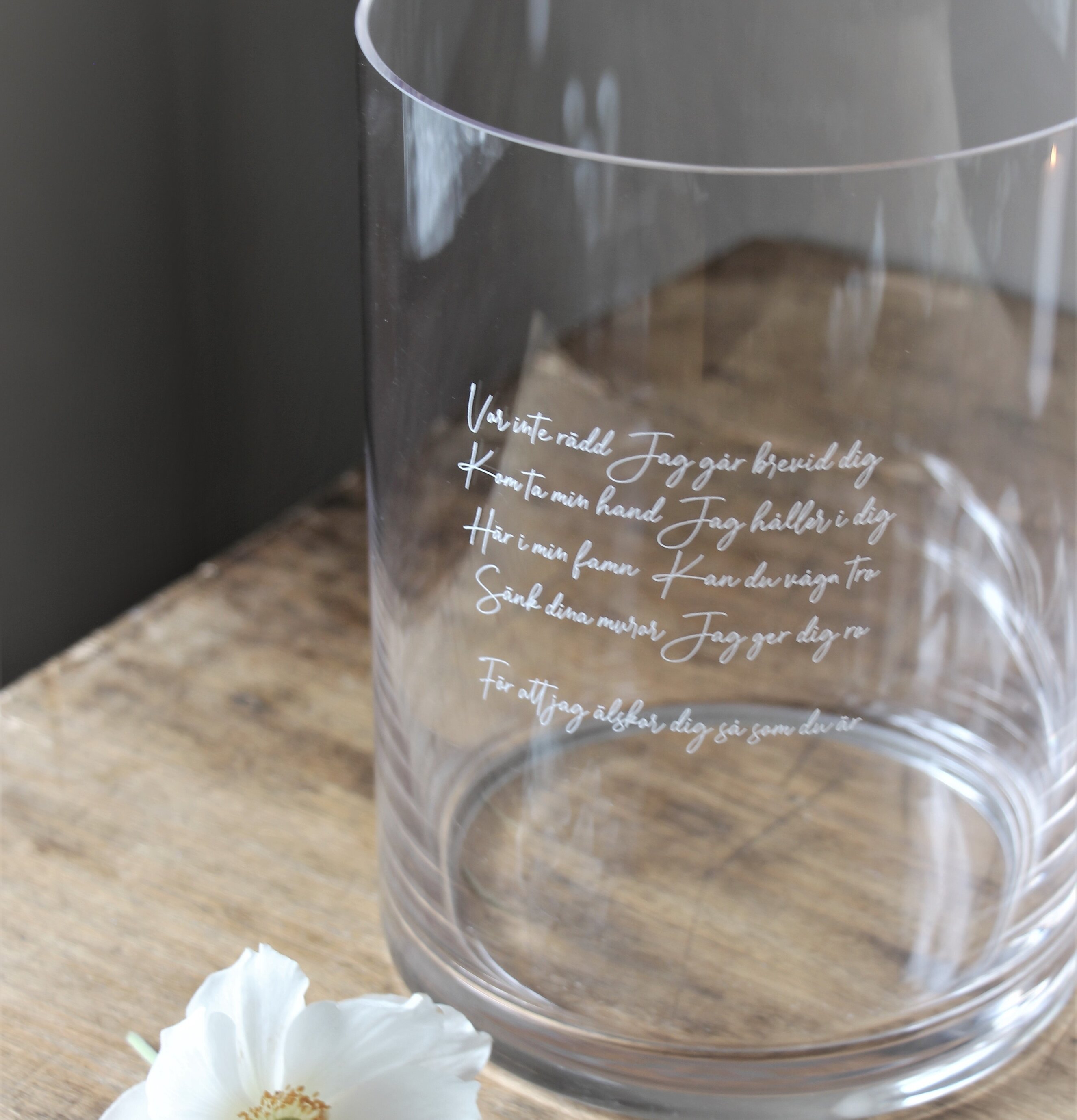 Bild av elegant glasvas med graverad text och blomma