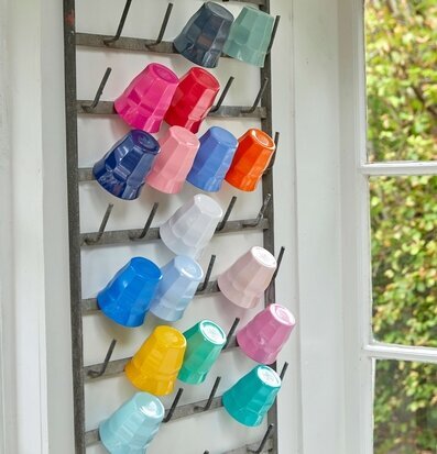 Foto av färgglada melaminmuggar på metallställning