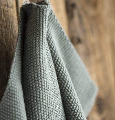 Handduk Mynte Mossgrön från IB Laursen mot rustik träbakgrund