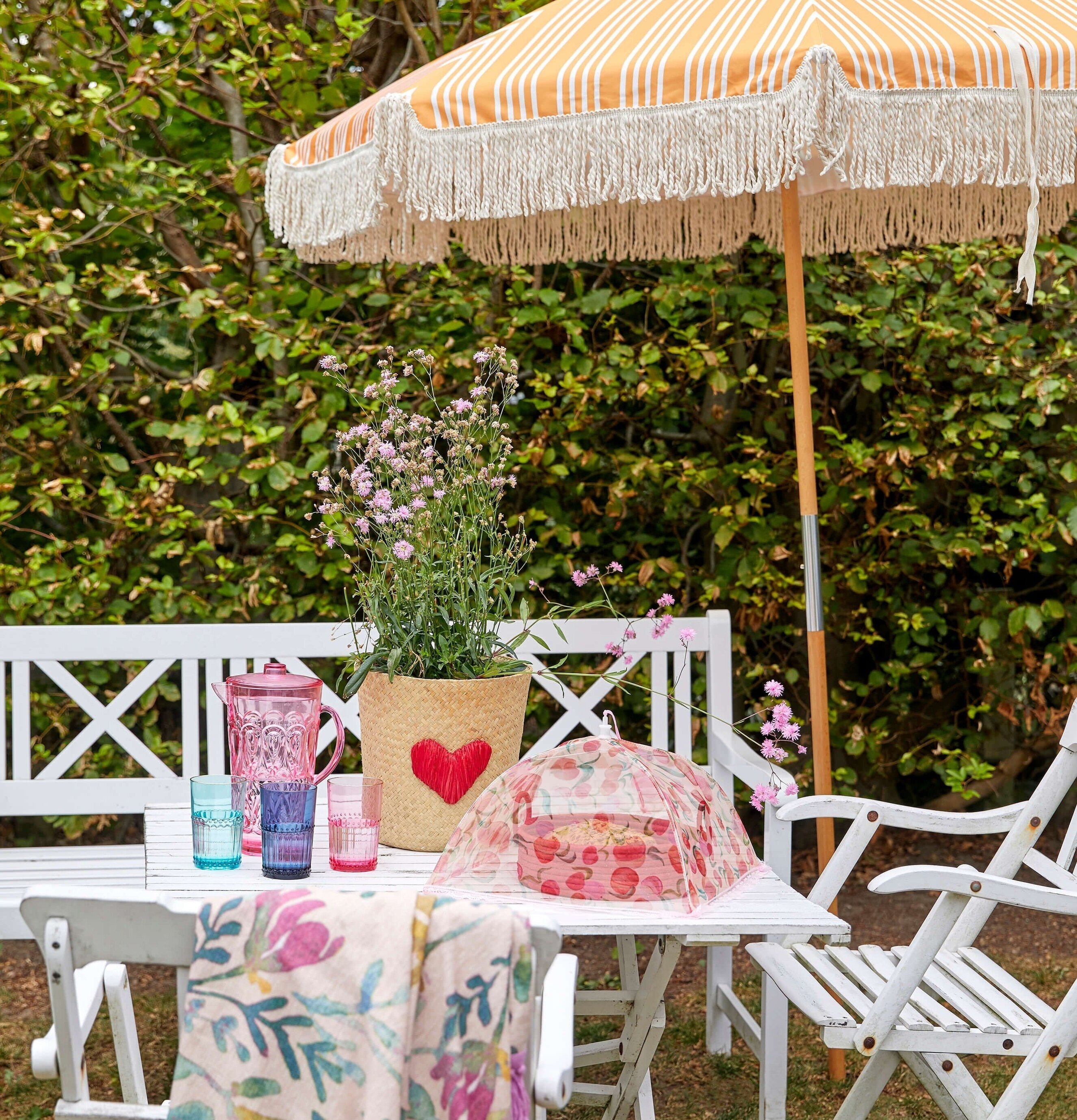 Vikbart Matskydd Peach Print från Rice på ett trädgårdsbord