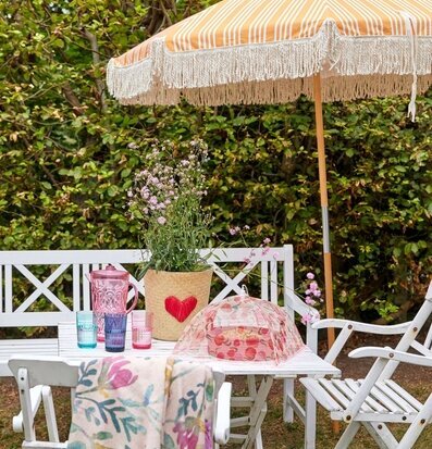 Vikbart Matskydd Peach Print från Rice på ett trädgårdsbord