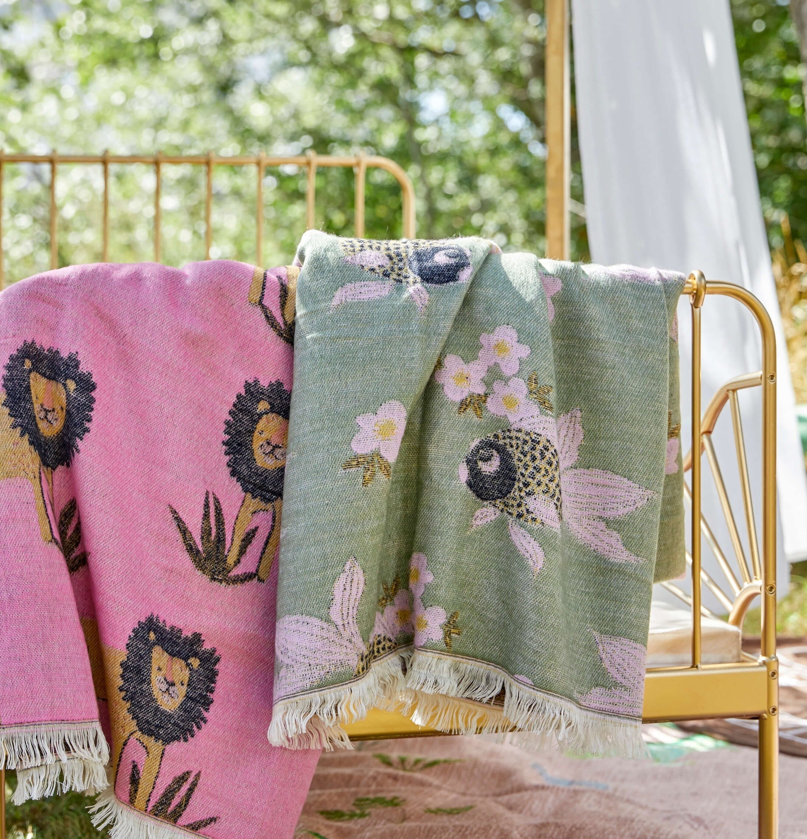 Pläd Goldfish Sage Green från Rice hänger över guldsäng