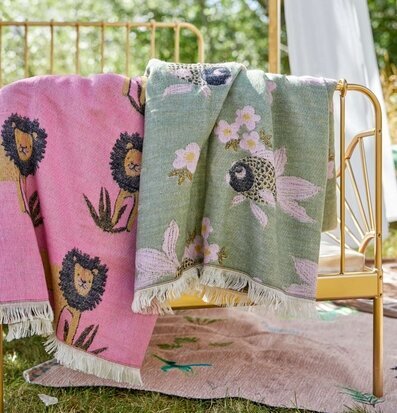 Pläd Lions Bubblegum Pink från Rice i en trädgårdsmiljö