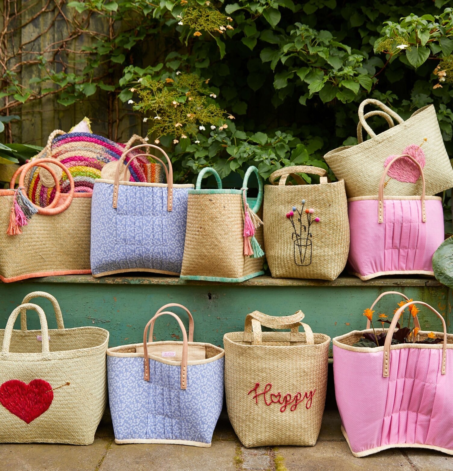 Väska Raffia Pom Pom Coral från Rice mot grön bakgrund