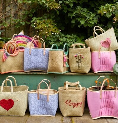 Väska Raffia Pom Pom Coral från Rice mot grön bakgrund