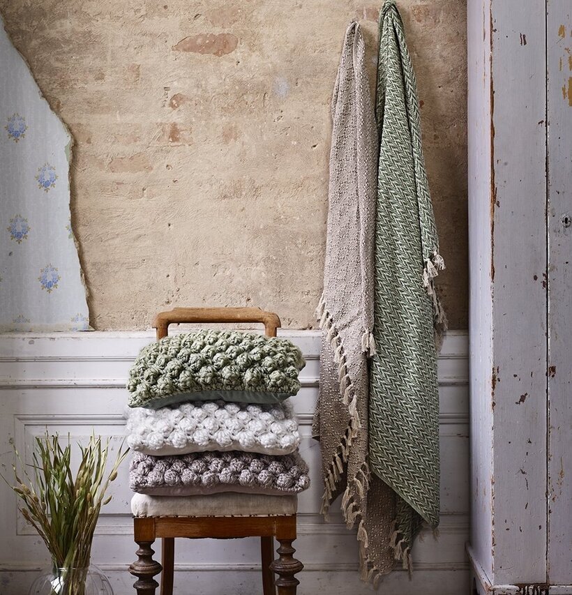 Pläd Hedvig Beige från Strömshaga hänger på krok vid vägg