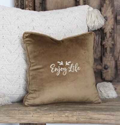 Kudde Enjoy Life från Majas Cottage på en rustik träbänk