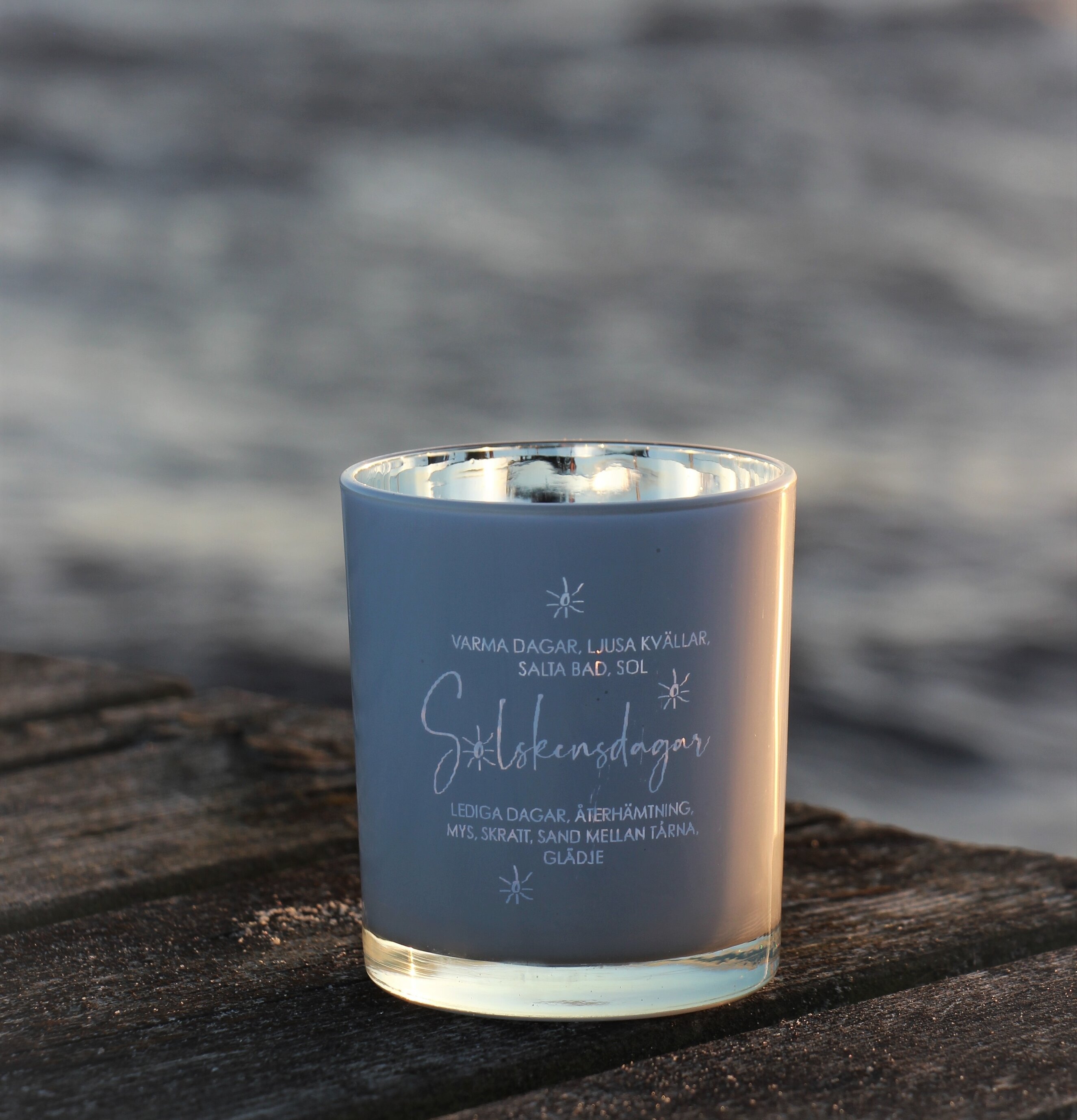 Bild av ljuslykta på bryggdäck i somrig atmosfär