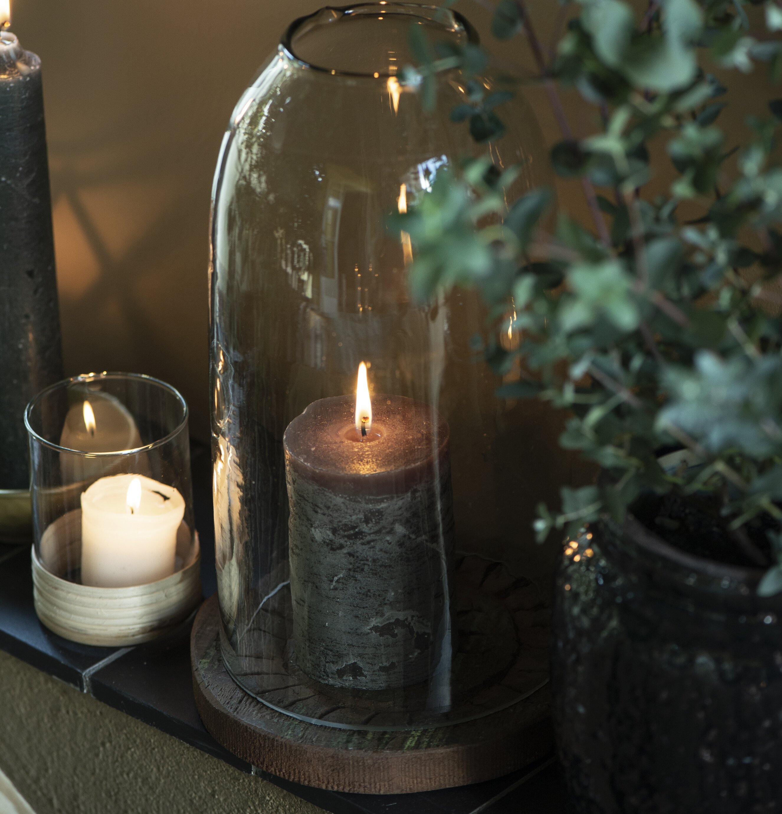 Glasklocka från IB Laursen med tända ljus på träplatta