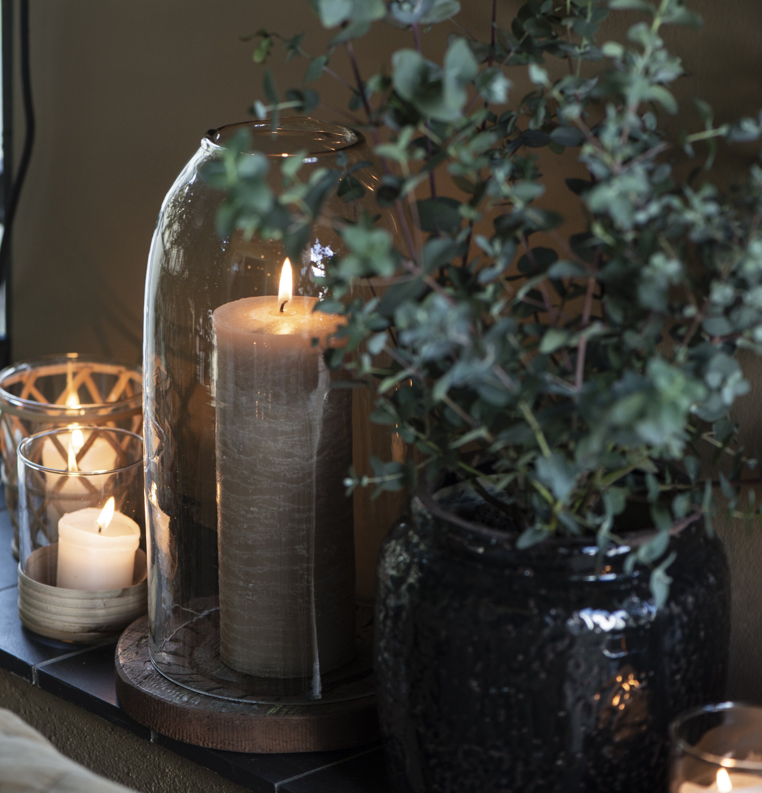 Glasklocka från IB Laursen med tänt ljus på träskiva