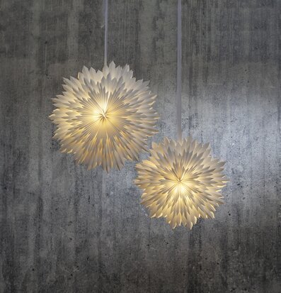 Pappersstjärna Ice Vit från Star Trading framför betongvägg