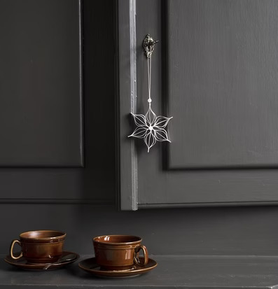 Dekoration Stjärna från Watt och Veke hänger på en mörk dörr