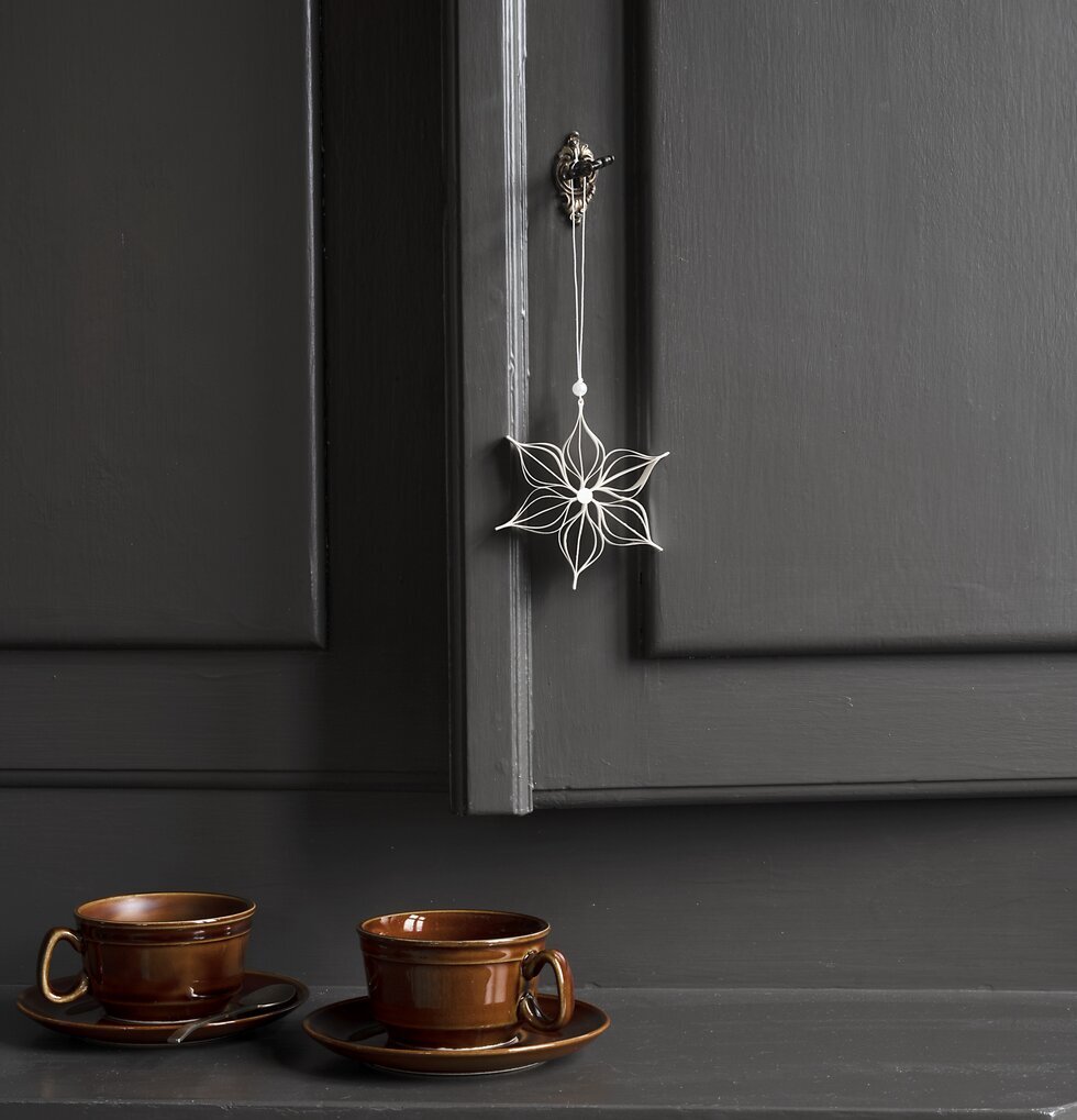 Dekoration Stjärna från Watt och Veke hänger på en mörk dörr