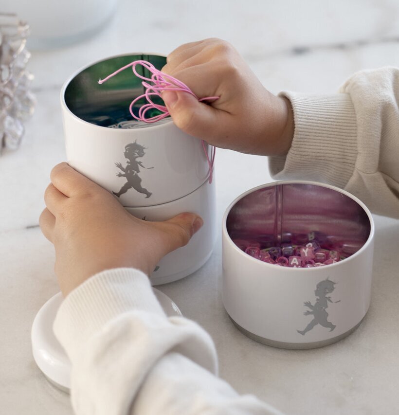 Bild av vit förvaringsburk med barnhänder och pärlor