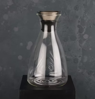 Glaskaraff från Multi Agentur på svart piedestal mot grå vägg