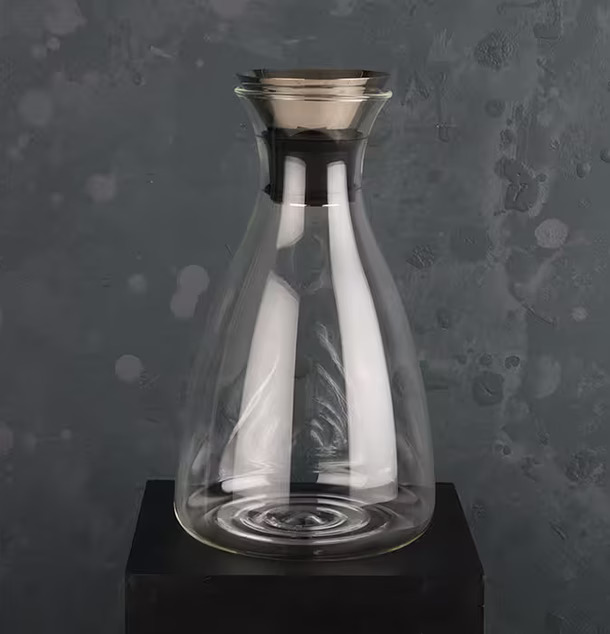 Glaskaraff från Multi Agentur på svart piedestal mot grå vägg