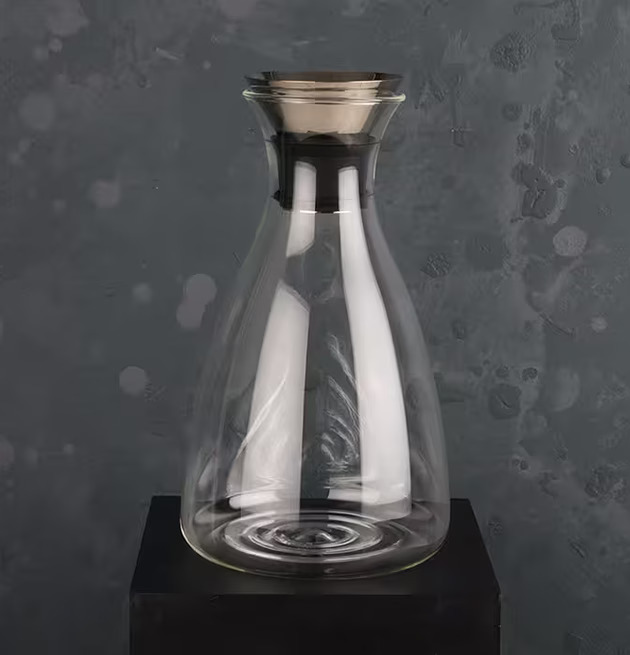 Glaskaraff från Multi Agentur på svart piedestal mot grå vägg