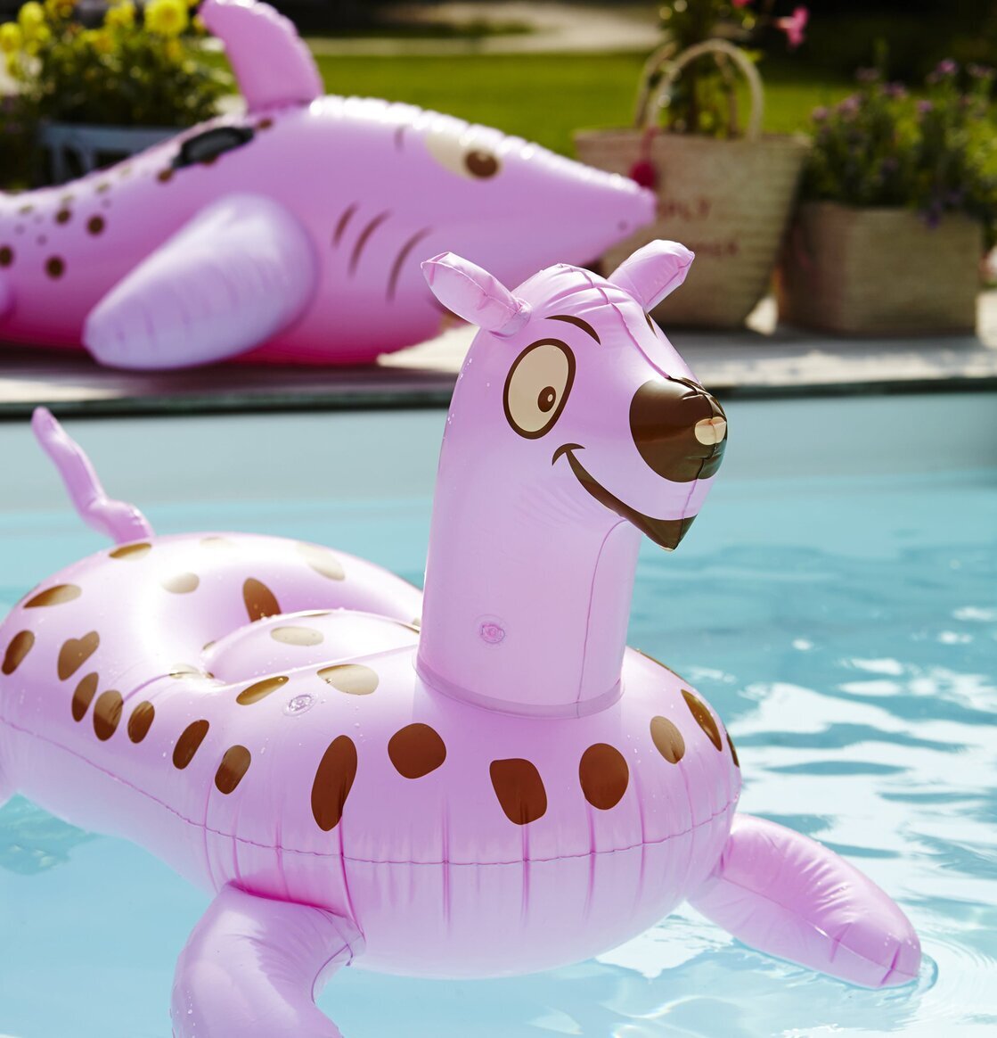 Tiger Uppblåsbar Rosa från Rice i en ljusblå pool med växter