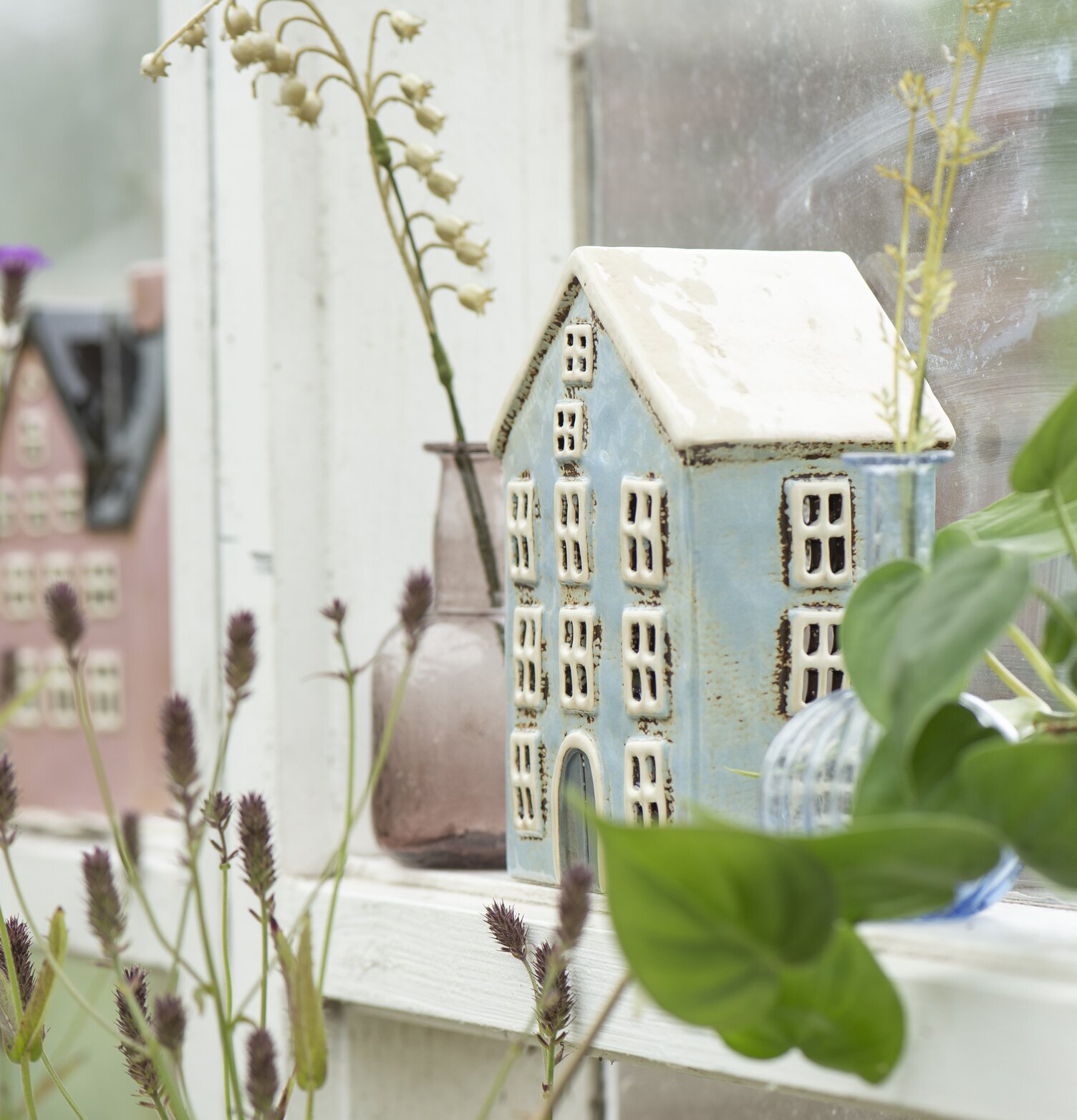 Bild av charmiga husformade ljuslyktor i växthus