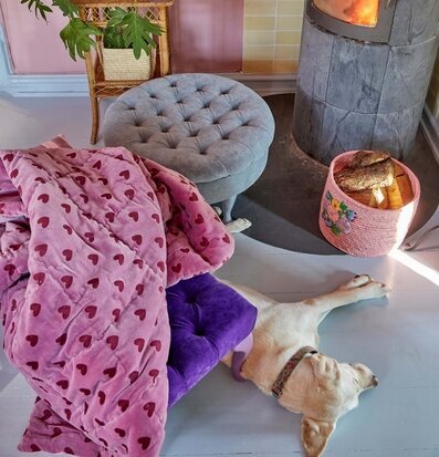 Quilt Hearts Purple/Maroon från Rice på golv bredvid ottoman