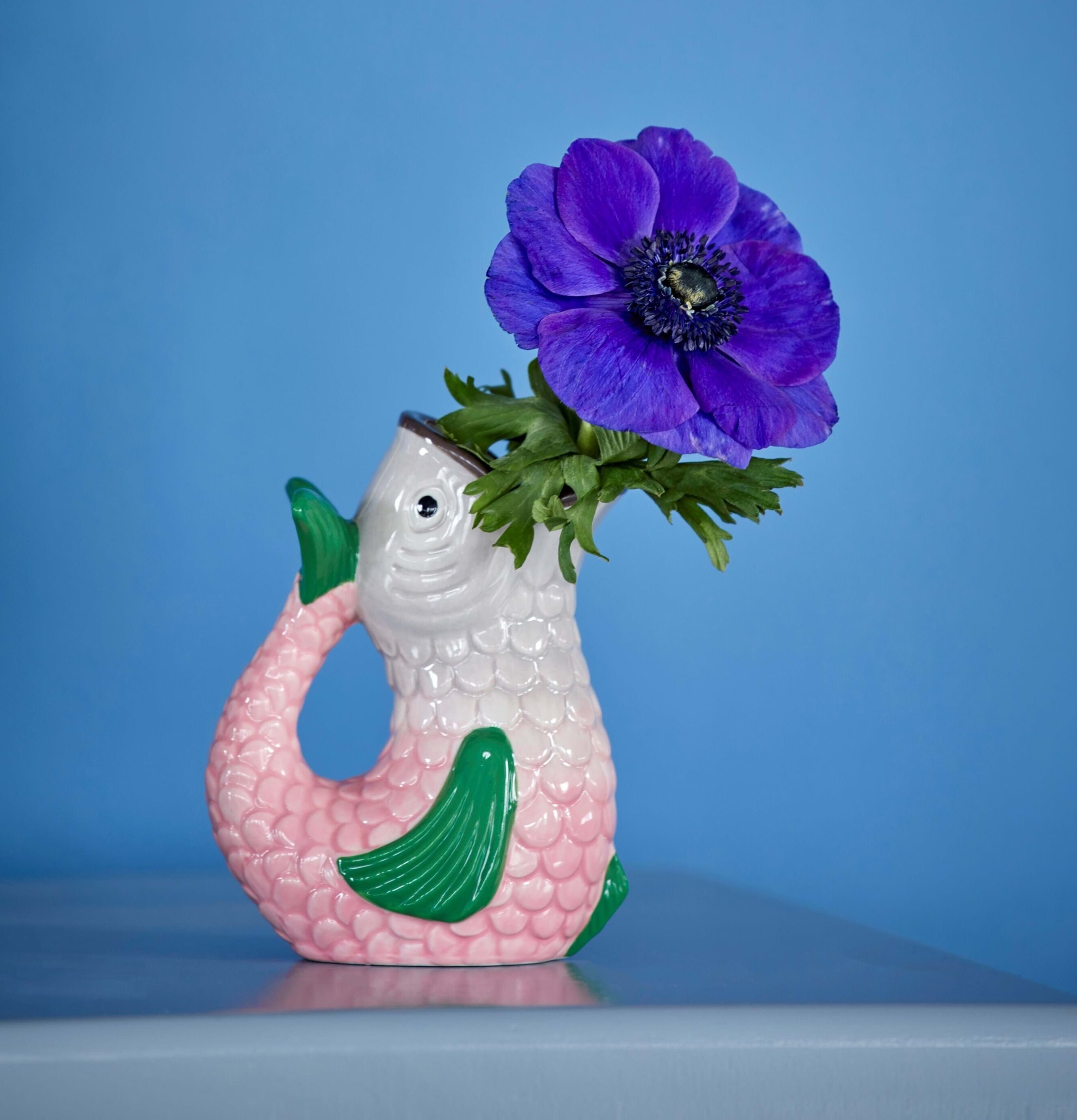 Vas Fish Shape från Rice med lila blomma och blå bakgrund