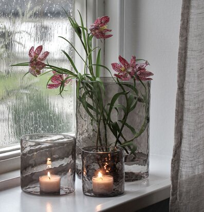 Bild av stilrena ljuslyktor i regnvåt fönsternisch