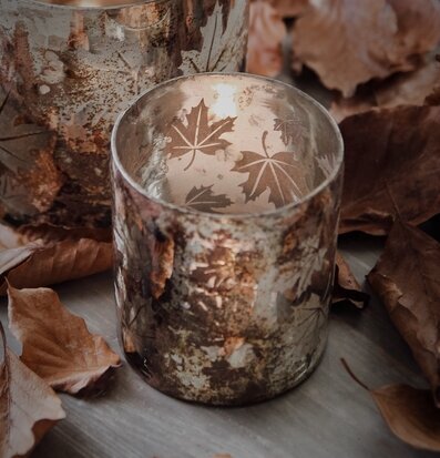 Foto av ljuslykta med höstlöv och varm stämning