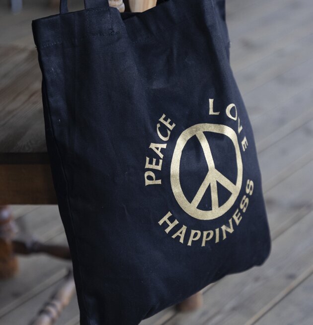 Väska Canvas Peace från Different Design hänger på trästol