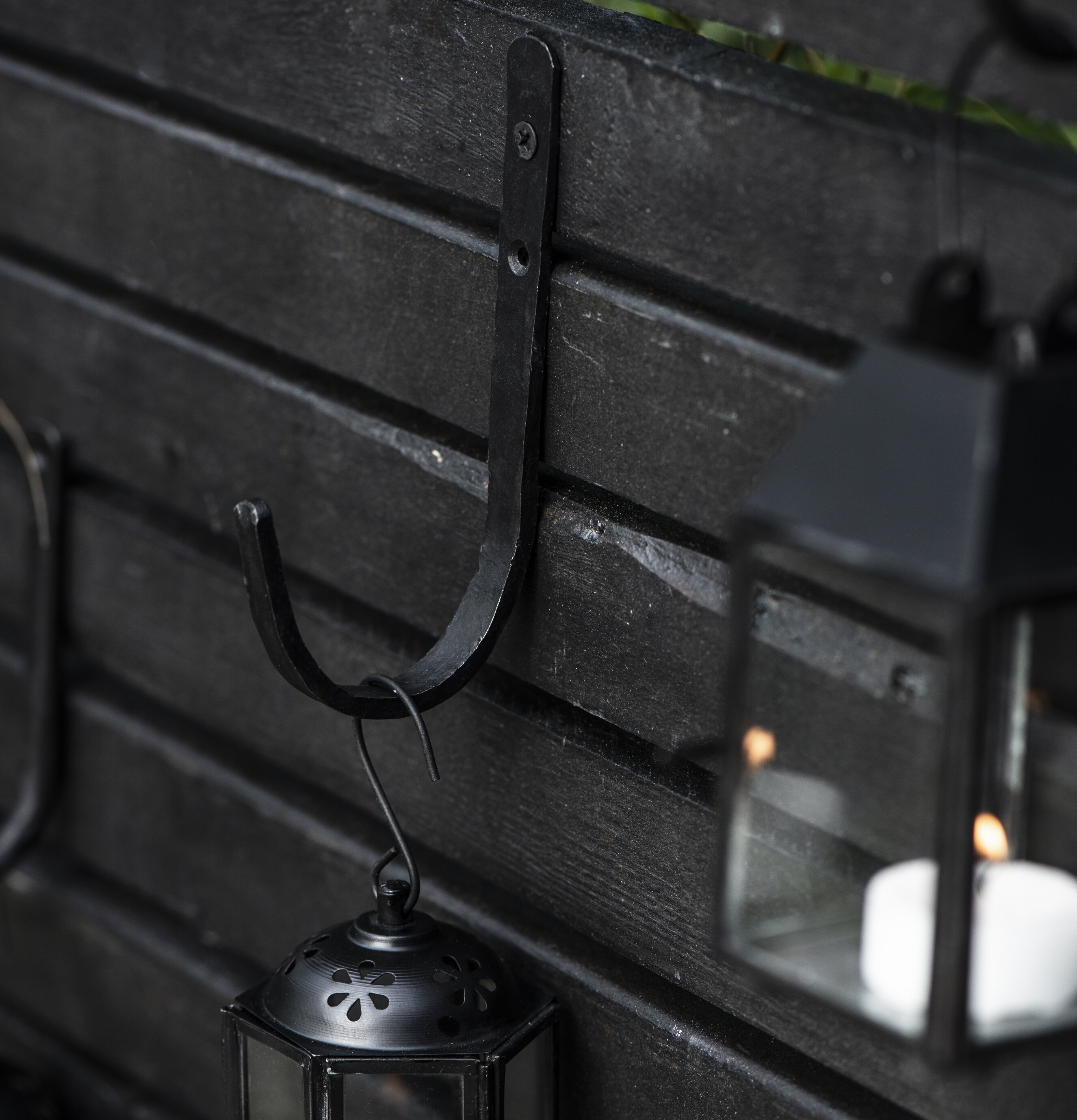 Krok Smide från IB Laursen på en mörk trävägg med lykta