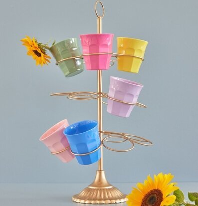 Bild av färgglada muggar på gyllene ställ med solrosor