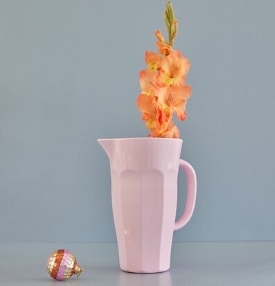 Kanna Melamin Rosa från Rice mot gråblå vägg med blomma