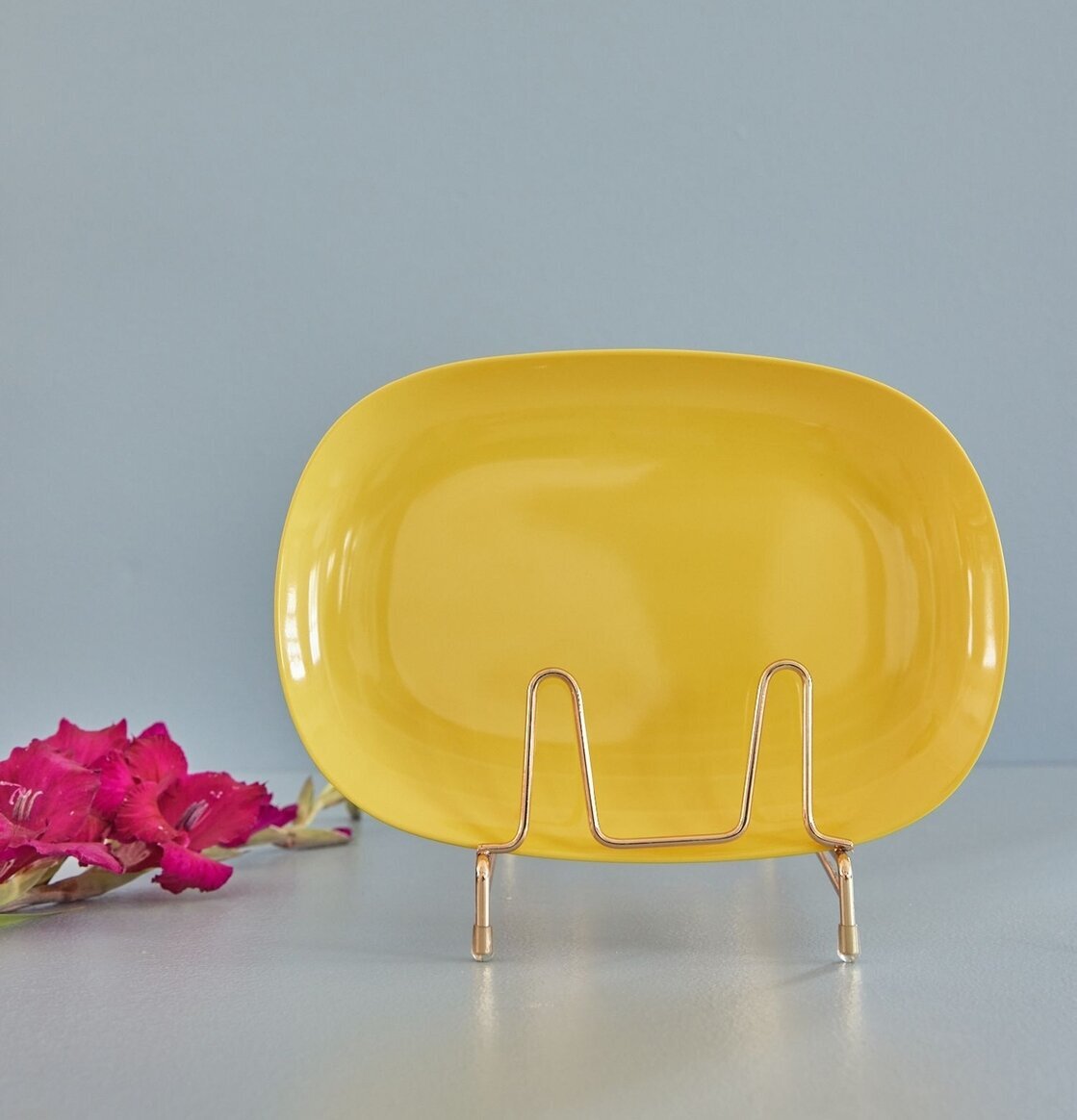 Tallrik Large Yellow från Rice på guldställ med grå bakgrund