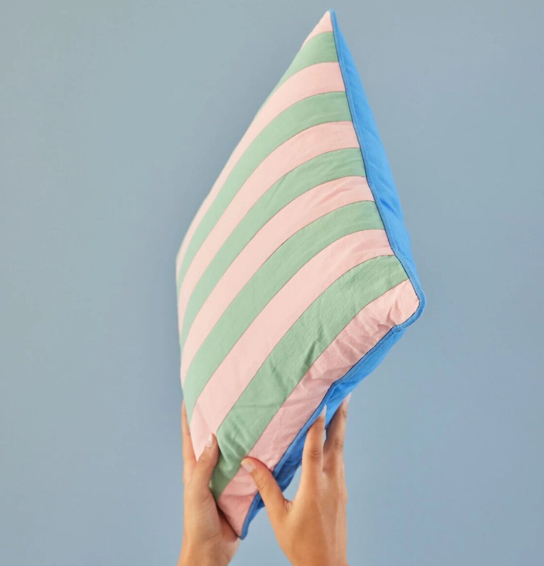 Kudde Striped Print Pink/Green från Rice hålls upp mot vägg